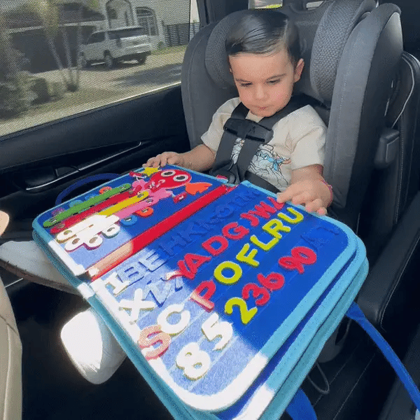 Toddlers playing with a felt busy book in the car